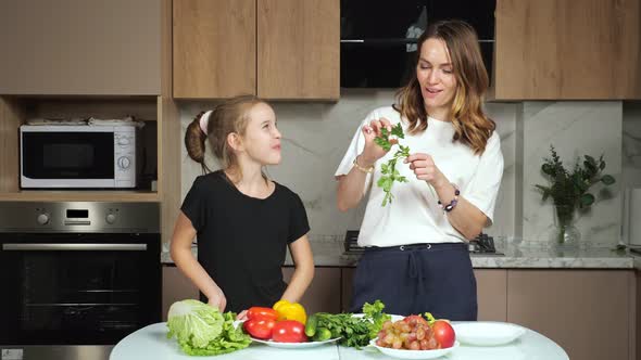 Mother Gives Teen Daughter to Taste Parsley in Kitchen