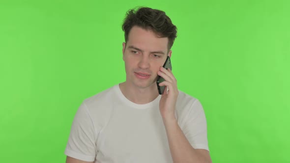 Young Man Talking on Phone on Green Background