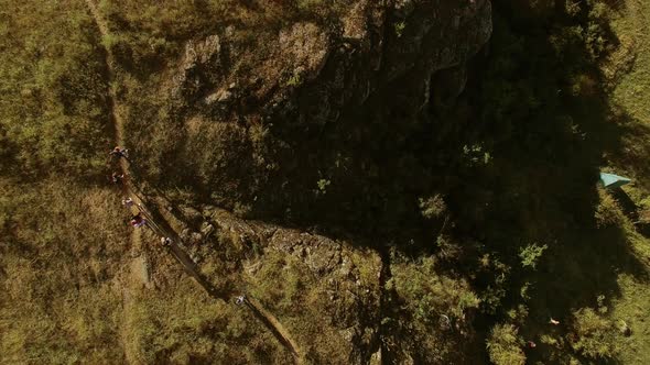 Flyover Top View From Drone of Tourist's Group Walking on Road to Camping Through Rocky Steppe