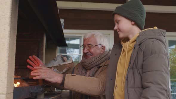 Child Watching Granddad Warming Hands by Fire