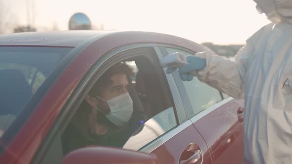 Doctor Using Infrared Thermometer Gun To Check Body Temperature of Driver
