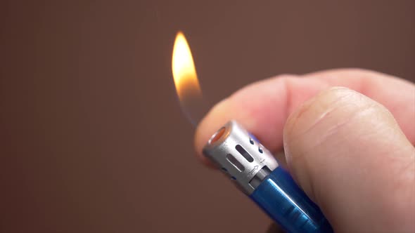 Male hand ingniting gas lighter with forefinger,blurred background.Close up shot.