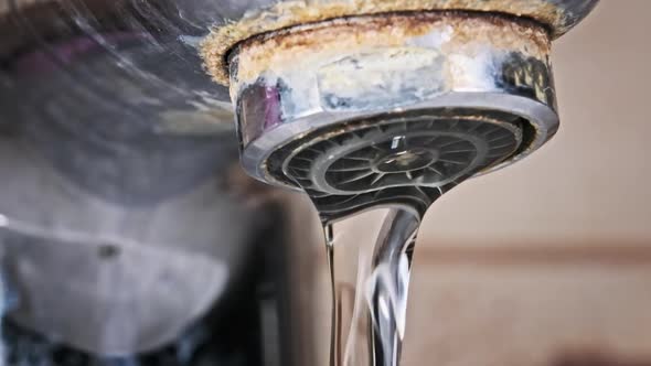 Water Flows From an Old Contaminated Tap with Calcium and Grime Into a Sink