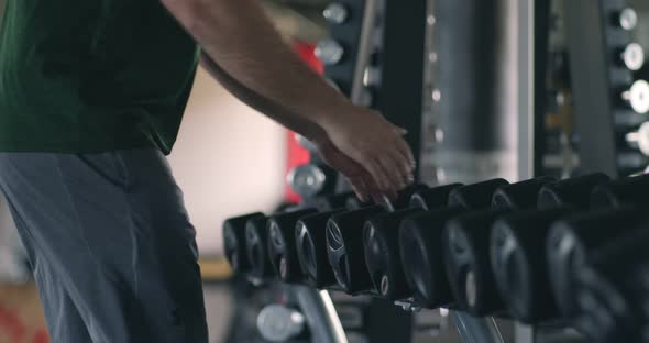 Close Up of Overweight Man Taking Dumbbells From Rack at Gym, Slow Motion