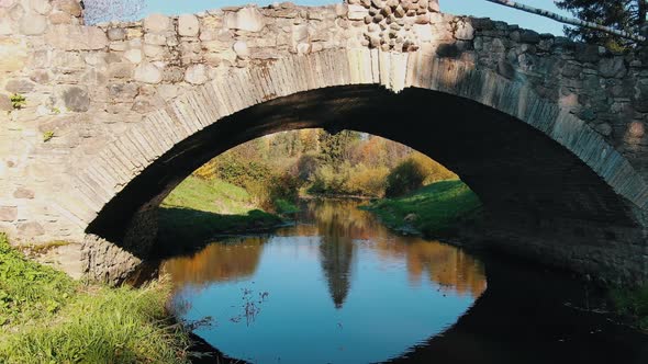 Old Dark Stone Bridge Situated Over Stream in Autumn Park