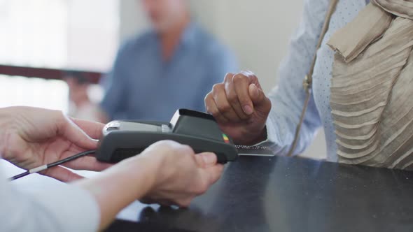 Biracial woman paying with credit card at reception at modern dental clinic