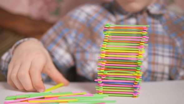Boy Builds a Pyramid of Colored Sticks