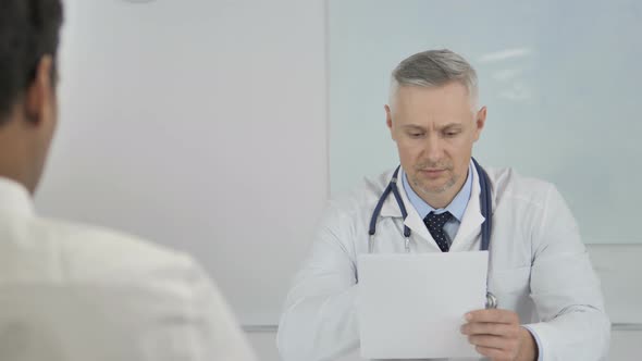 Grey Hair Senior Doctor Giving Prescription To Patient After Discussing Results