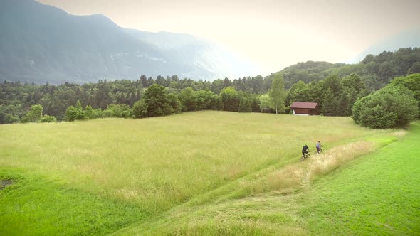 Aerial view of a couple driving mountain bikes by rural dirt road outdoors.