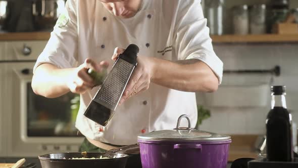 chef grates fresh lime zest on metal grater. Cooking at restaurant's cuisine.