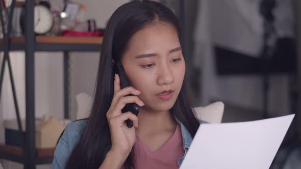 Young Asian woman talking on Phone and reading documents.