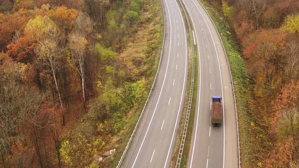 Truck Drives Into Distance on Freeway Amid Yellow Trees in Fall - Coming Into Shot