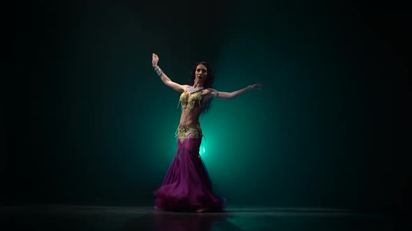 Woman in Exotic Shining Moves Her Tummy . Smoke Background