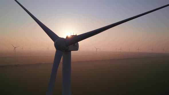 Close-up of wind turbine blades at sunset or sunrise.