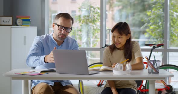 Teacher Sitting at Desk with Asian Female Student Teenager Study Together