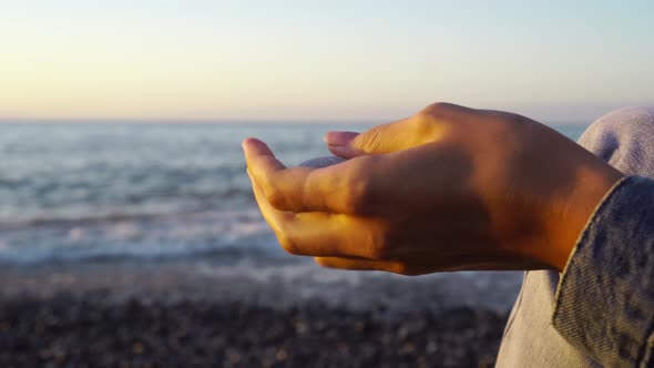 Hand holds pebbles on a background of sea and sun