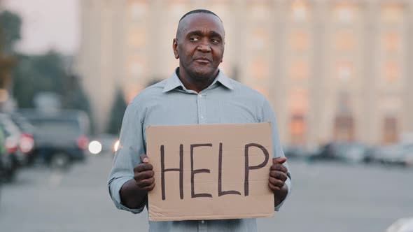 Unhappy Black African American Businessman Holding Cardboard with Text Help Emotional Pointing on