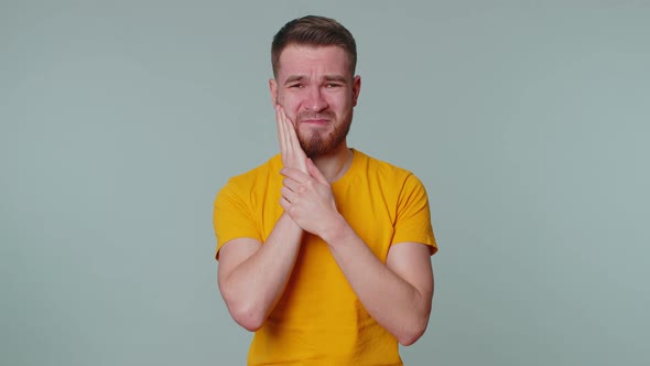 Man Touching Cheek Suffering From Toothache Cavities or Gingivitis Waiting for Dentist Appointment