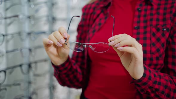 Female buyer holding new spectacles in the optical store