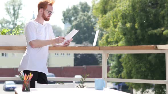 Young Designer Reading Documents, Standing in Balcony Outdoor