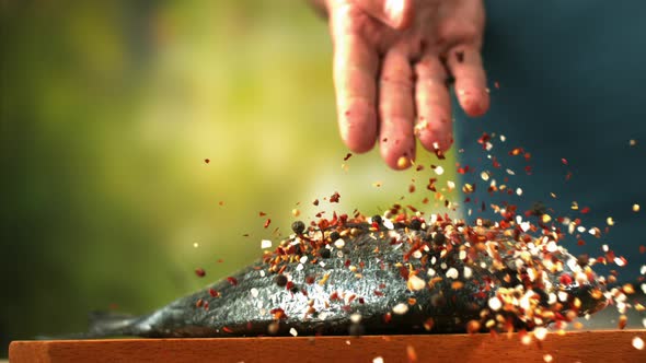 Male Chef Seasoning Fresh Dorado Fish With Pepper And Salt A Close Up Of Hand Sprinkling