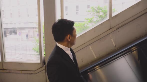 Japanese businessman taking the escalator