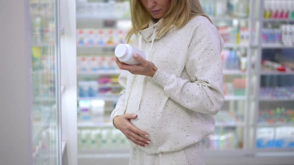 Positive Unrecognizable Pregnant Woman Caressing Belly Choosing Pills in Drugstore