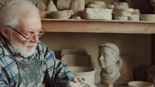 Elderly Potter Working with Assistant in Workshop