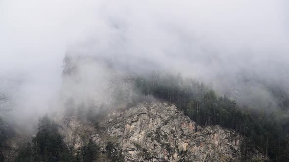 Timelapse Steep Mountain Slopes Covered with Coniferous Pine Forest with Sharp Rocks. Low Clouds