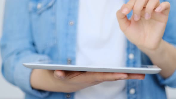 Close Up on the Hand of Young Handsome Woman Pointing and Touching the Screen of a Tablet with Her