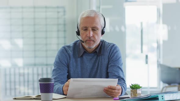 Man wearing headset talking while sitting on his desk at office