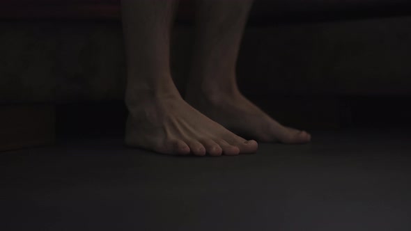 Dark Morning Shot of Man Feet on the Floor Near Bed