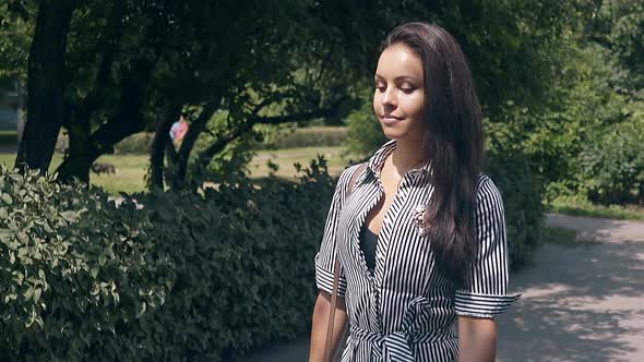 Wonderful Girl in Summer Dress with Stripes Walks in Park