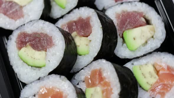 Close up sushi rolls otating. Japanese food with avocado, salmon, tuna.