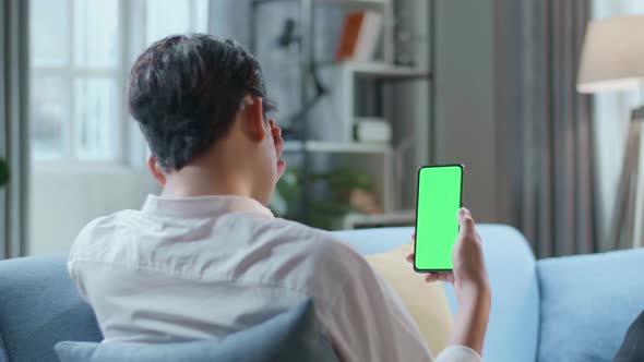 Man Being Tired While Lying On Sofa And Using Green Screen Smartphone In The Living Room