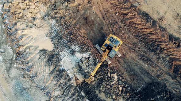 Top View of a Borrow Pit with an Excavator Digging Ground