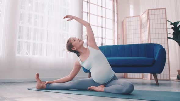 Asian pregnant woman doing yoga exercise at home.