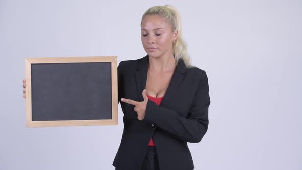 Young Serious Blonde Businesswoman Holding Blackboard and Giving Thumbs Down
