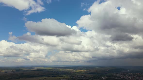 Aerial View From High Altitude of Distant City Covered with Puffy Cumulus Clouds Forming Before