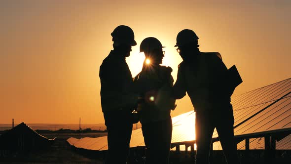 Silhouettes of Solar Energy Industry Workers on a Solar Farm