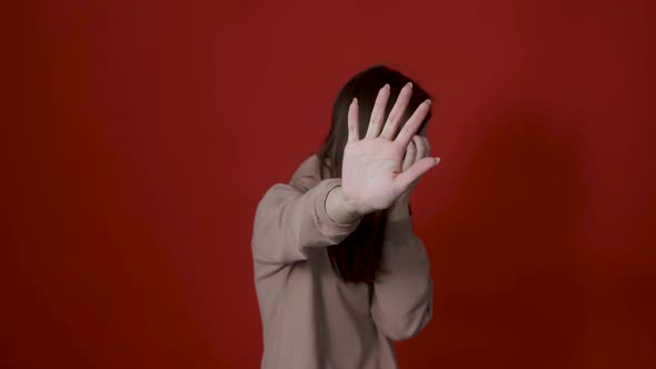 Portrait of Confused Girl in Checkered Shirt Covering Eyes with Hand and Showing Stop Gesture