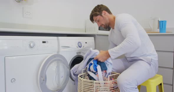 Man putting clothes in washing machine at home 4k