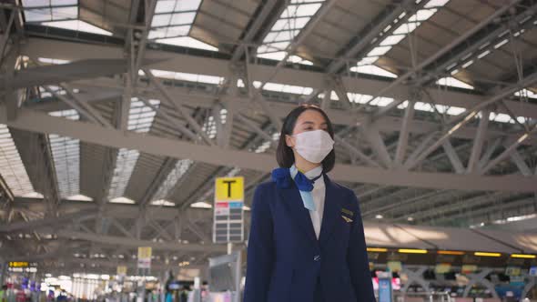 Cabin crew or air hostess wearing face mask walking in airport terminal to the airplane due to Covid