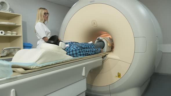 Woman doctor makes knee-joint MRI scanning.