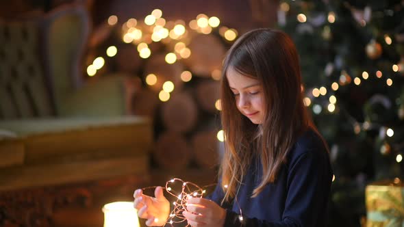 Happy cute girl holding bright festive garlands in her hands and dreaming