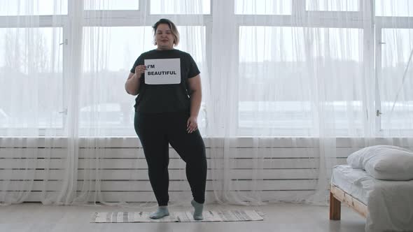 A Confident Overweight Woman Holding a Nameplate with a Sign I'M BEAUTIFUL