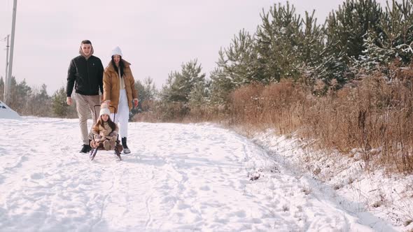 Young Family Walking Near Forest in Countryside in Winter