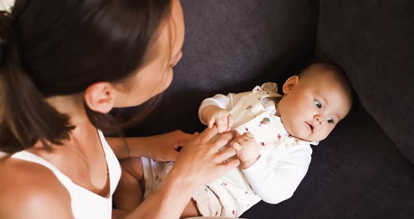 A Young Mother is Babysitting Her Newborn Daughter  She Entertains Her and Touches Her Little Nose