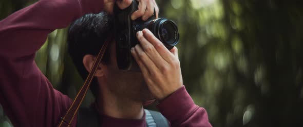 Man focuses and takes photo in forest