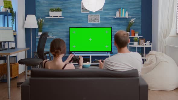 Static Tripod Shot of Young Woman and Boyfriend Gaming Online Having Fun on Green Screen